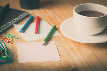 Notebook and sticky paper, paper clip, color pencil, and pen on wood table with vintage filter effectの写真素材