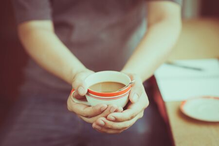 The man wearing grey t-shirt holding coffee cup in his hand in afternoon timeの写真素材