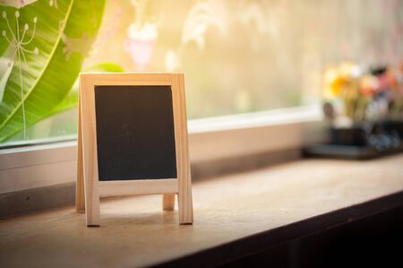 Small A-frame black board with blank area for text or message on wood bar in cafeの写真素材