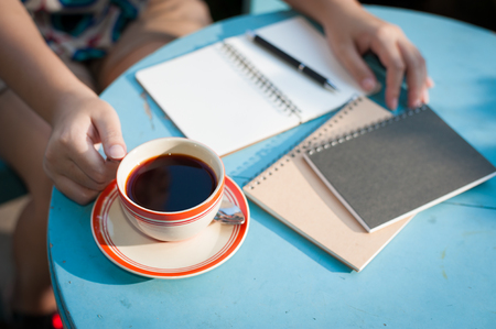 Woman right hand holding coffee cup during coffee break in cafe with morning sceneの写真素材