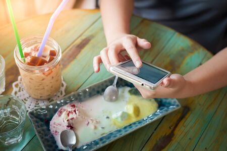 Afternoon scene of young woman using smartphone for social networking in cafe on weekend. Trendy...