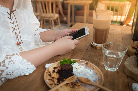 Weekend lifestyle scene of young woman using phone in cafe. Trendy lifestyle with technology conceptの写真素材