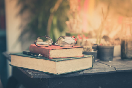 Glasses with books and pen on wood table in morning time. weekend lifestyle concept. focus on red...