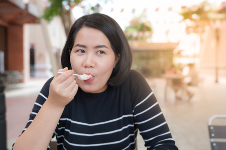 Adult Asian woman eating dessert at coffee shop on weekend. Urban lifestyle on weekend concept.の写真素材
