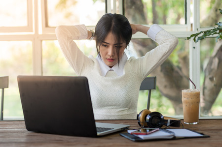 Young Asian woman freelance worker taking a break while working with laptop computer in coffee shop. Startup business and self-employed activity conceptの写真素材