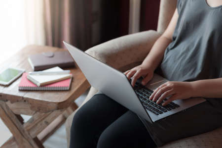 Woman typing on laptop computer keyboard while using internet for online activity. Wireless working and internet of things conceptの写真素材
