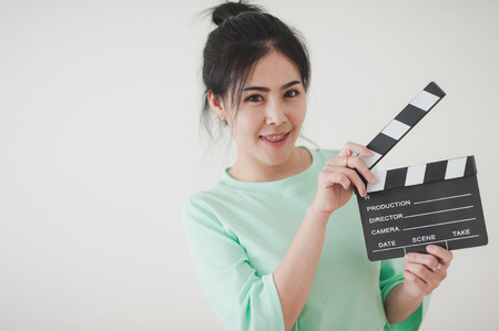 Young attractive Asian woman holding clapperboard with positive feeling. Film production and movie making conceptの写真素材