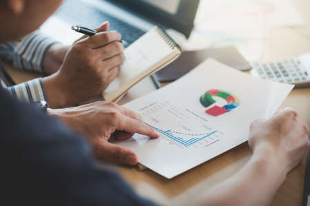 Businessman hand holding report document in office meeting room with business discussion and brainstorm atmosphere in blurry background.の写真素材