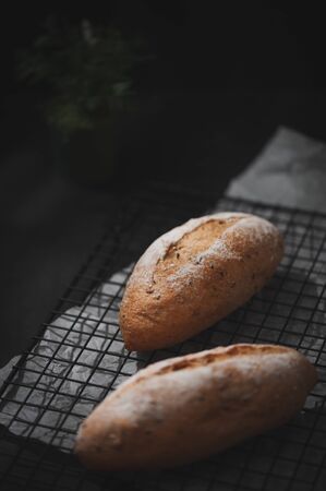 Baguette, European style bread on black wood table in morning time with hard light effect.の写真素材
