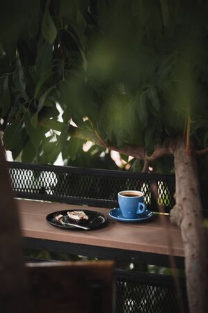 Abstract scene of coffee break meal set including black coffee, and brownie cheese cake on outdoor wood barの写真素材