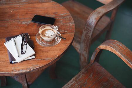 Abstract scene of coffee cup, notebooks,and mobile phone on rustic wood table.の写真素材
