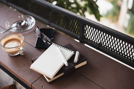 Abstract scene of coffee cup, notebooks,and mobile phone on rustic wood counter.の写真素材