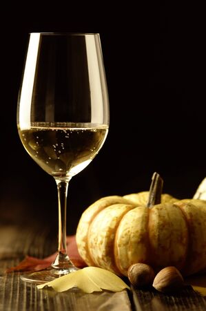 Autumn theme; pumpkins, leaves, white wine  Riesling  and hazelnuts on rustic surfaceの写真素材