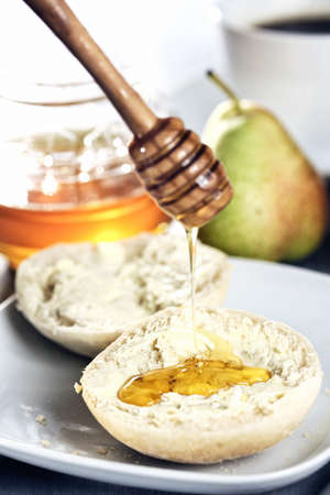 Breakfast; buttered roll with honey dripping on it, focus is on honey on the rollの写真素材