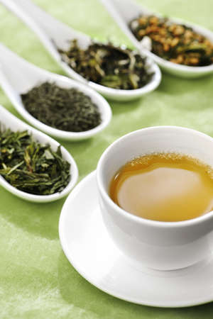 Cup of green tea with different sorts of loose green tea in the background, selective focusの写真素材