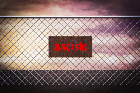 Wooden racism sign on wire mesh demonstrating racism danger and discrimination risk concept. 3D illustrationの写真素材