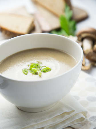 Creamy mushroom soup served in a white bowl with some decorations on the side.の写真素材