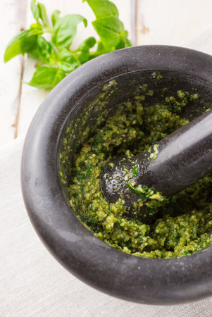 Green basil pesto in a black pestle and mortarの写真素材