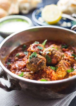 A silver bowl full of meatballs in tomato sauce in a dark rustic settingの写真素材