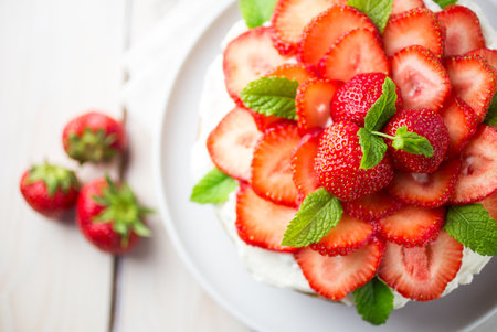 South american tres leches cake topped with strawberries and cream in a white settingの写真素材
