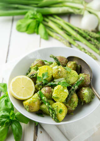 Bowl of potato salad with pesto, asparagus and lemon in a light and airy settingの写真素材
