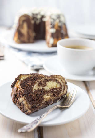Marbled gugelhupf cake topped with chocolate glaze and white chocolate crumbs in a white settingの写真素材