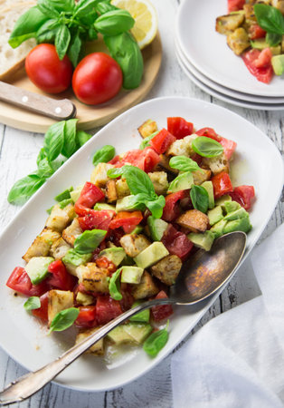 A big white plate full of italian panzanella salad with tomatoes, bread, avocado and basilの写真素材