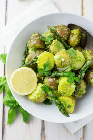 Bowl of potato salad with pesto, asparagus and lemon in a light and airy settingの写真素材