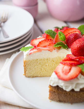 South american tres leches cake topped with strawberries and cream in a white settingの写真素材