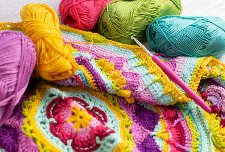 Colorful skeins of yarn arranged next to a crocheted blanket