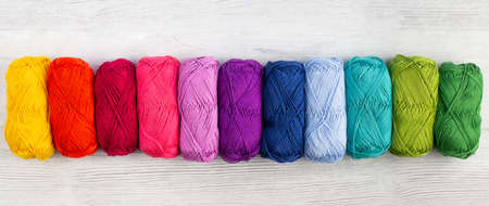 Rainbow colored skeins of yarn laid in a row on a light backgroundの写真素材
