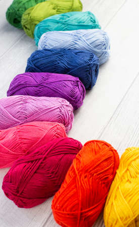Rainbow colored skeins of yarn laid in a curve on a light background
