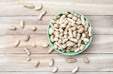 Top view peanuts in green bowl on wooden tableの写真素材