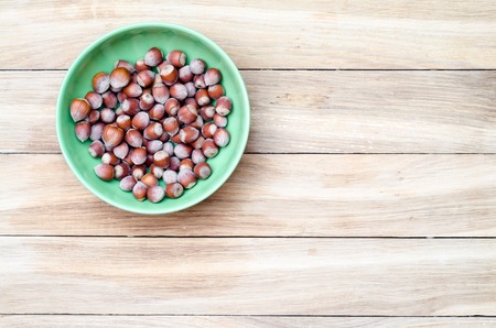 top view of hazelnuts in green bowl on wooden backgroudの写真素材