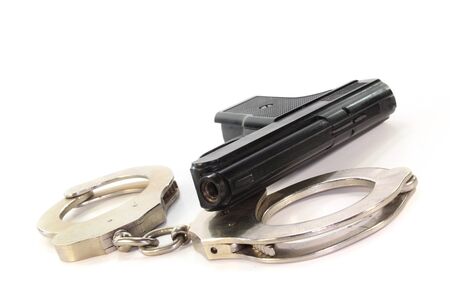 Handcuffs and a weapon on a white backgroundの写真素材