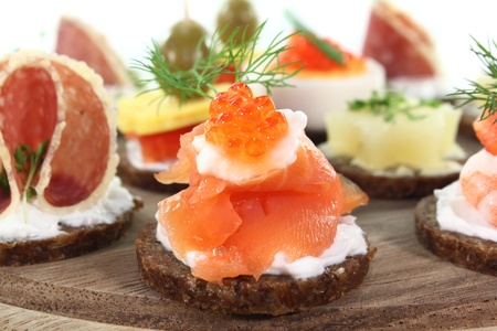 different canapes on a wooden board on a white background