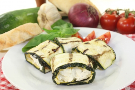 stuffed courgette rolls and tomatoes on a white plateの写真素材