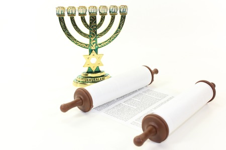Jewish candlestick and Torah scroll in front of white background