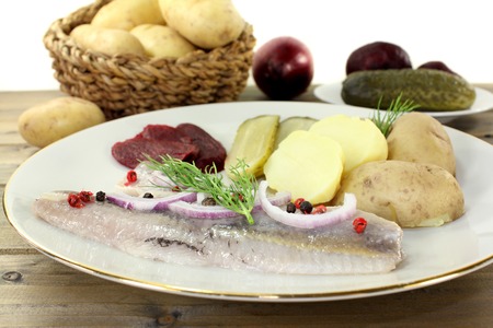 a plate of pickled herring fillet, boiled potatoes, beetroot and pickled gherkinsの写真素材