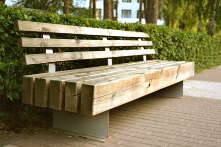 A wooden bench in the park alone on a sunny dayの写真素材