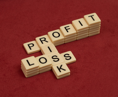 Crossword puzzle with words Risk, Profit and Loss. Risk management concept. Chart of ivory tiles with capital letters on red velure.の写真素材