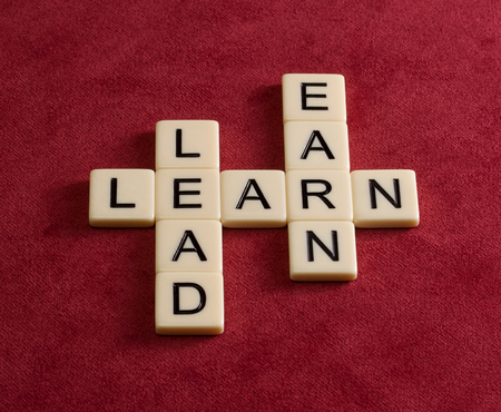 Crossword puzzle with words Learn, Lead and Earn. Leadership concept. Ivory tiles with capital letters on red velure.の写真素材