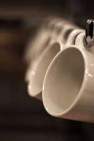 Close up Coffee cup hanging on a shelf with dark brown blurred background, Coffee brown tone.
