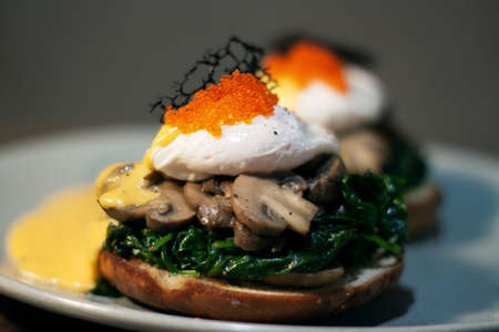 Poached egg with spinach, mushrooms topping with red caviar on burger. Wooden cutting board isolated on Dark Slate Gray Concrete Wall backgroundの写真素材