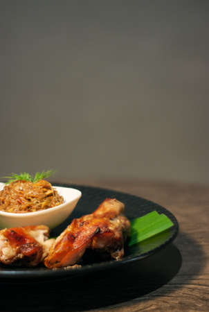 Thai grilled chicken wing on bamboo leave with traditional Thai blend of Fermented fish spicy dip on...