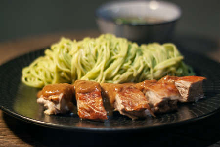 Green noodles (Jade Noodles) with Roasted duck and chicken broth, Asian food style, Chinese traditional street food. Black plate isolated on Dark Slate Gray Concrete Wall backgroundの写真素材