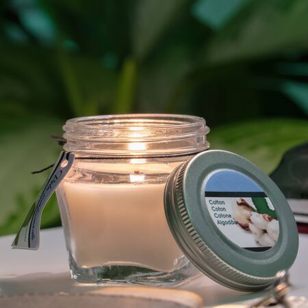 Scented Candle in Glass with Screw Cap on blurred Green Plant Backgroundの写真素材