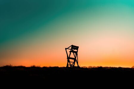 Colorful sunrise with a silhouette of a hunter high chairの写真素材