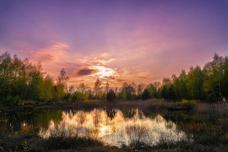 Sunset in purple mood on a lake with reflections on the waterの写真素材
