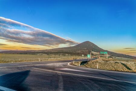 Farsighted view of a crossroads on the highway on mountains and colored skyの写真素材